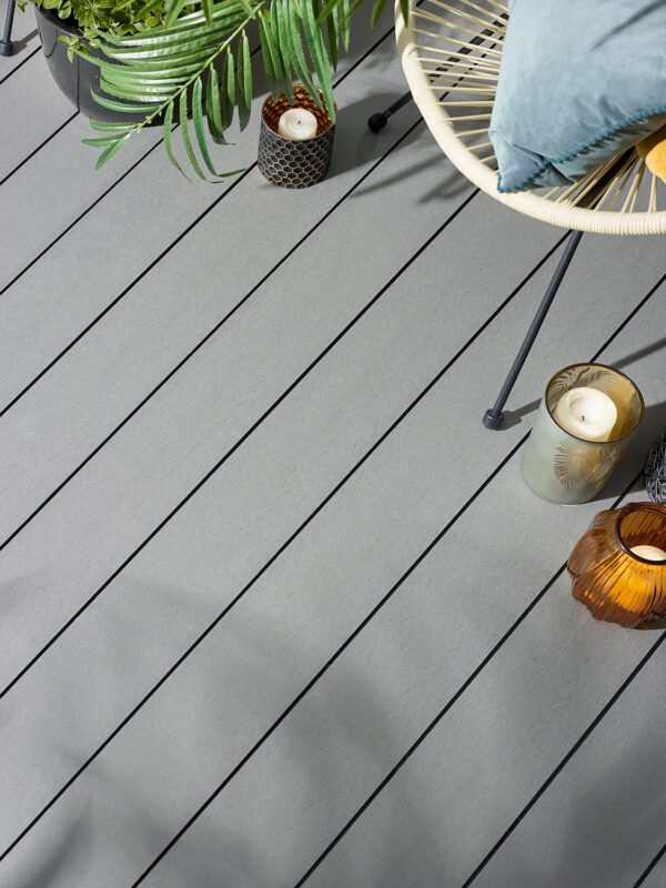 Close up of wood grain grey decking with small candles and cream garden chair