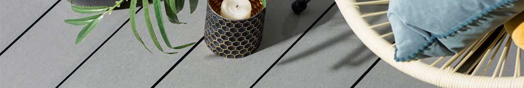 Close up of grey composite decking with candle and chair for frequently asked decking questions page