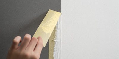 masking tape being pulled off painted wall